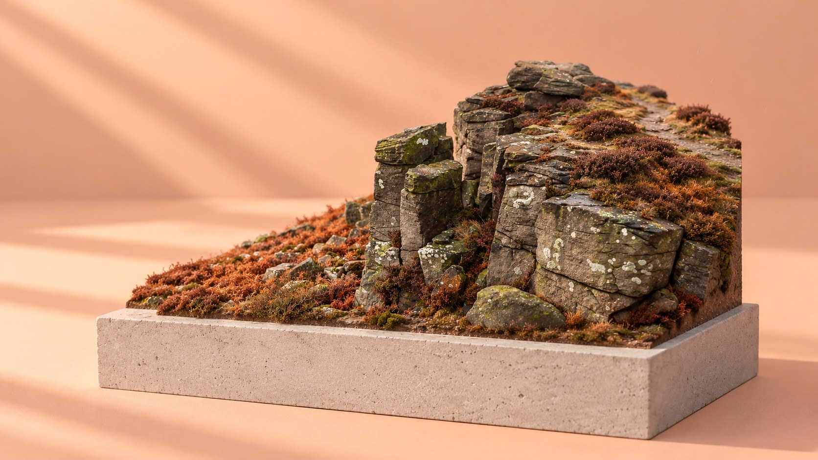 A sculpted miniature of Stanage Edge's gritstone crags and rust-coloured autumn bracken on a concrete plinth against a peach background