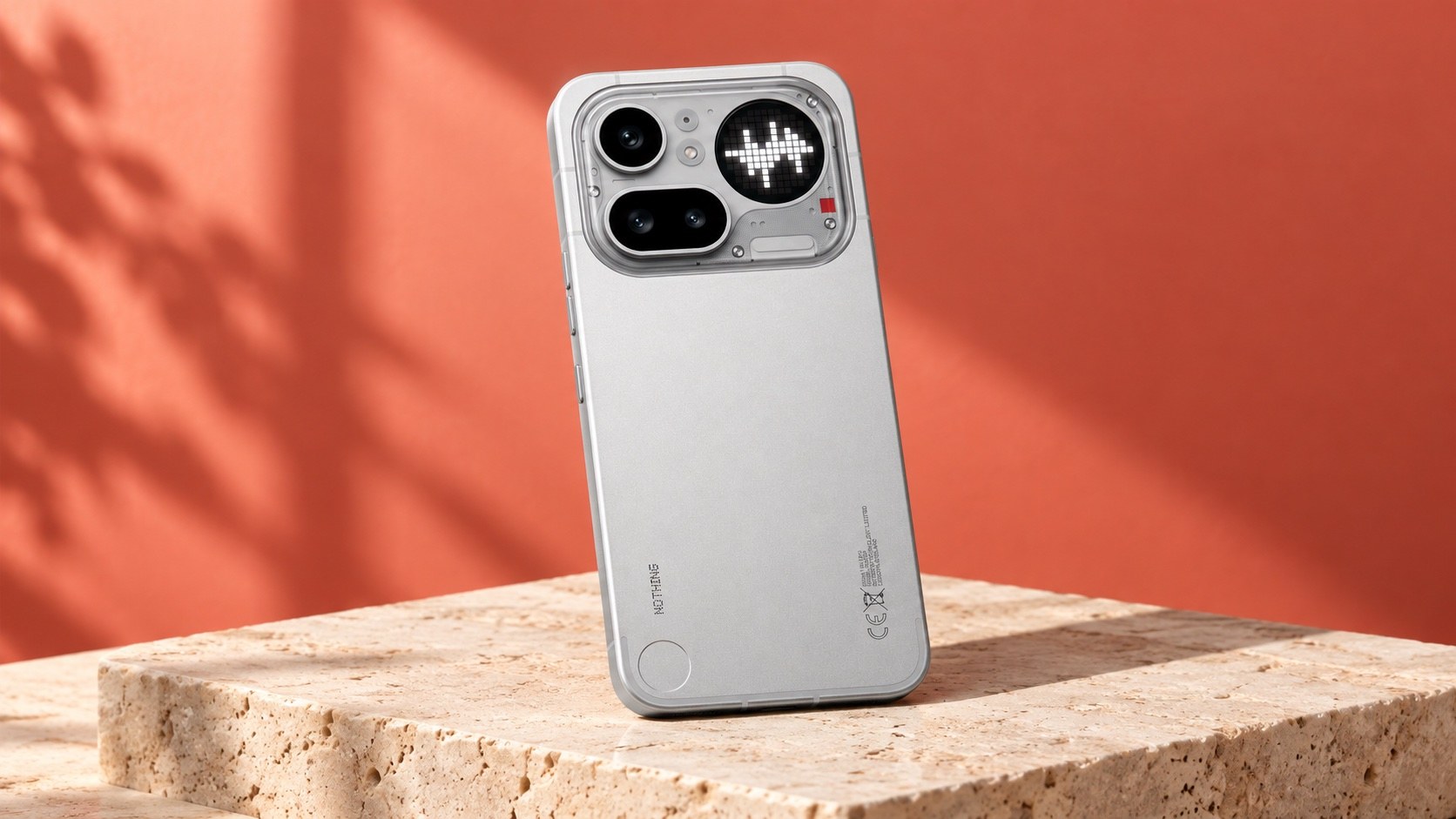 Silver Nothing phone on stone against a coral backdrop