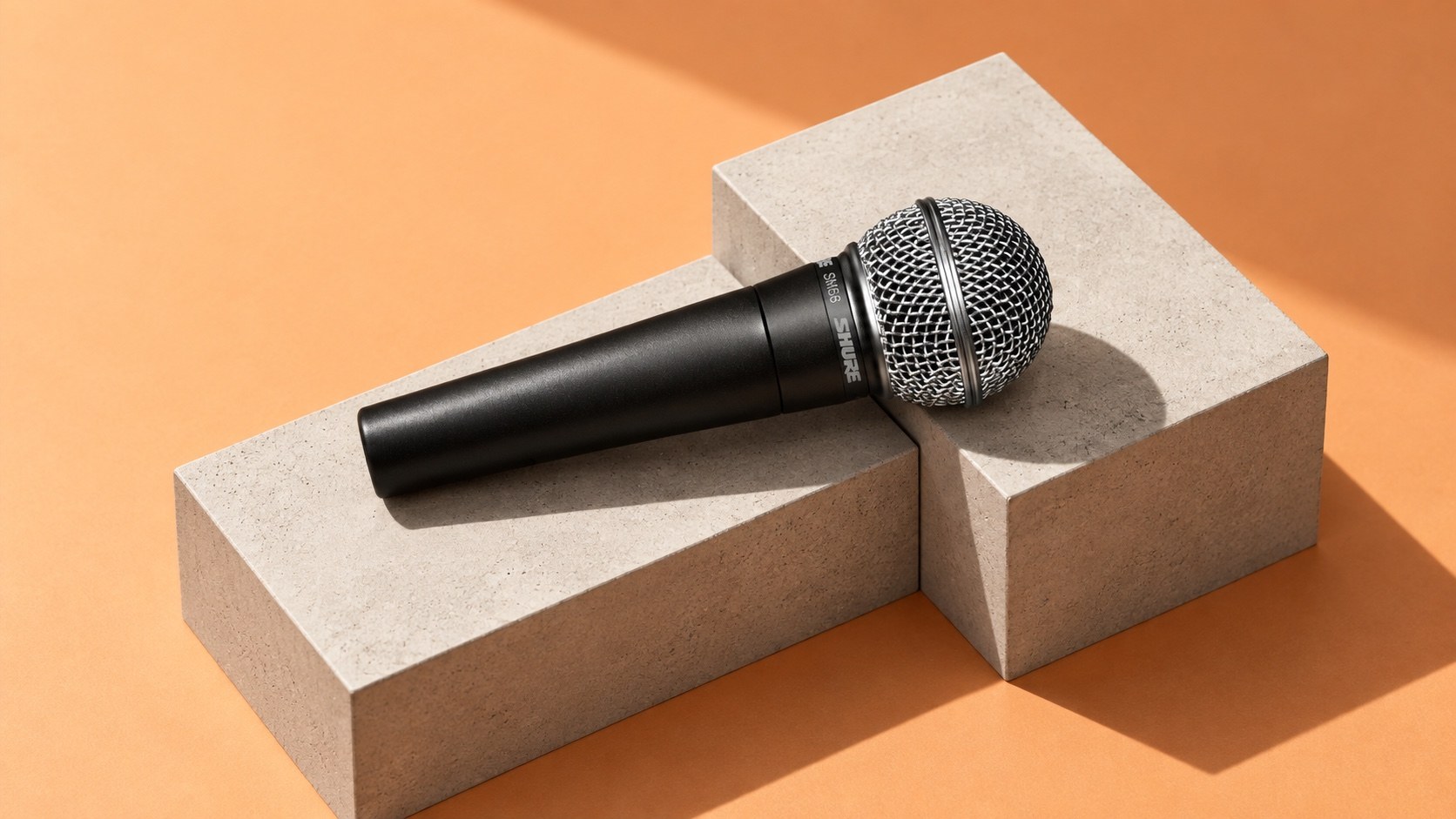 Shure SM58 microphone across pale concrete blocks against an apricot background